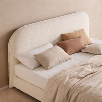 Bouclé upholstered bed with light bedding in a bright Mediterranean bedroom in Mallorca