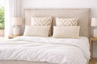 CHANEL upholstered headboard with French seam detail in natural beige fabric against a white wall. CHANEL upholstered headboard with French seam detail in natural beige fabric against a white wall.